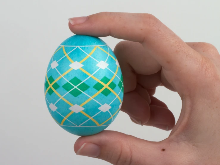 someone is holding an ornate patterned egg