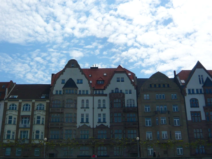 a row of old town buildings sitting under a cloudy blue sky