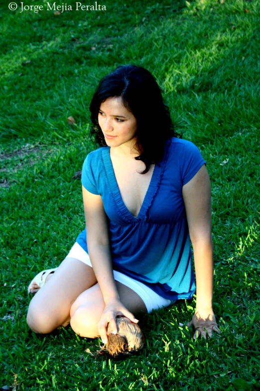 a girl sitting in the grass with her hand on her shoes