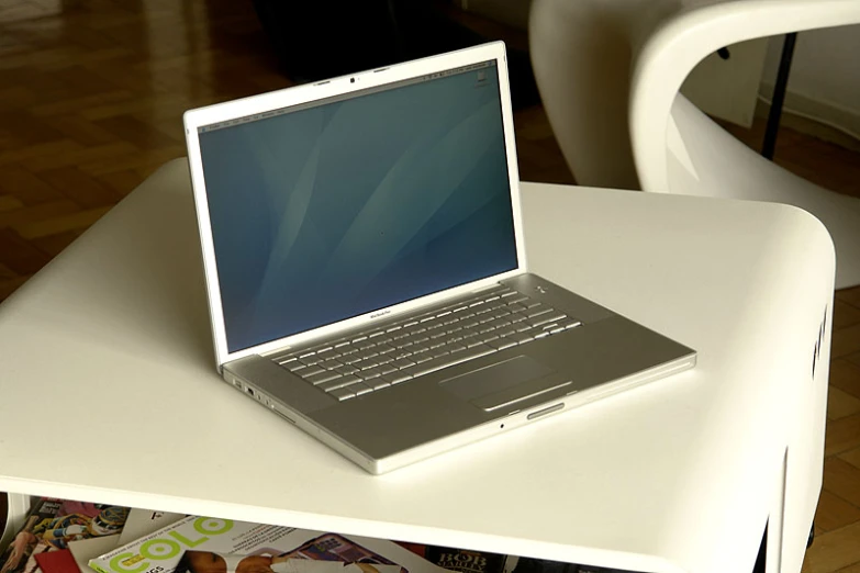 a laptop sits on the table top next to a chair