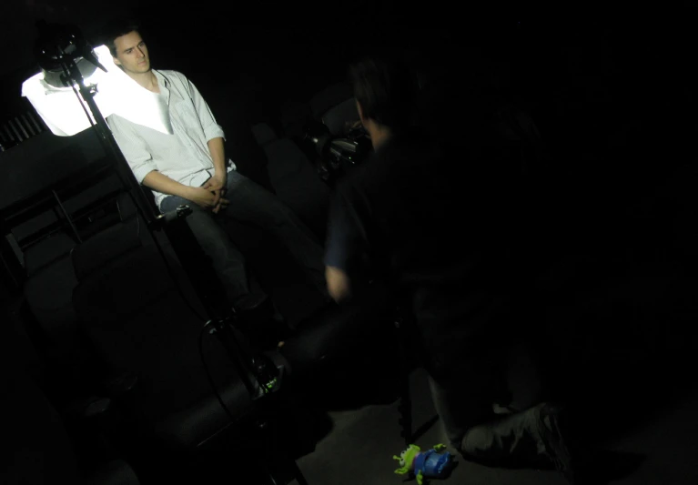 a couple of men standing next to a tv in a dark room