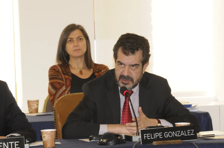 a man sitting in front of a table next to another man