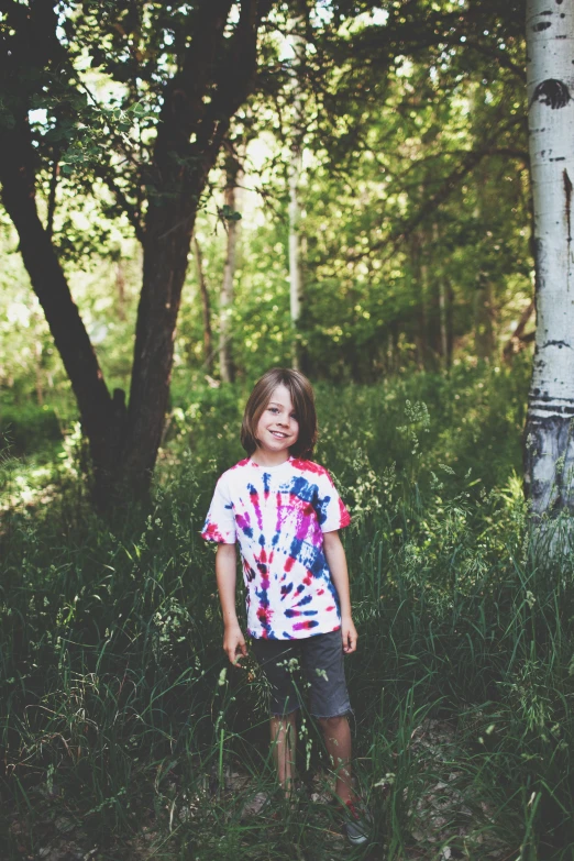 a girl smiles in the woods near a tree