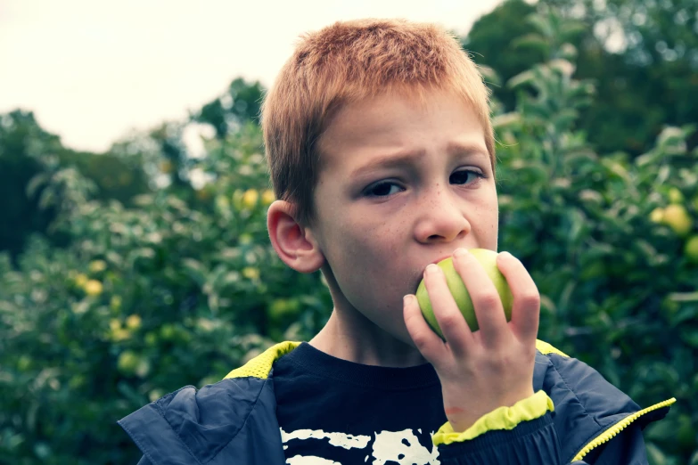 a  in black jacket biting into an apple