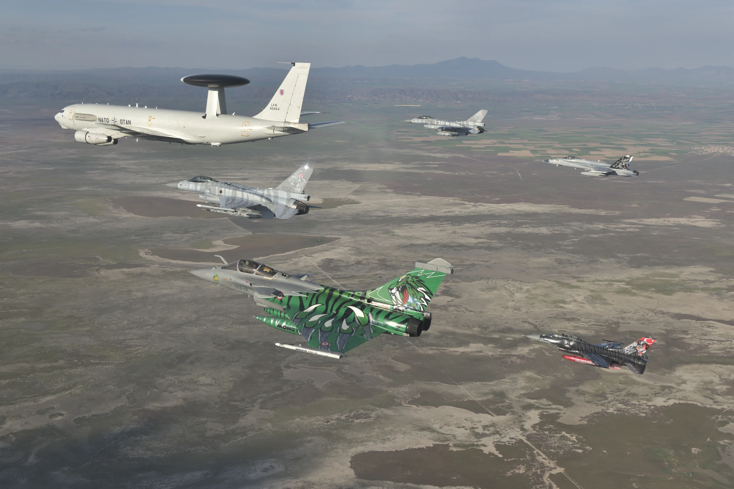 five airplanes flying in formation in an open field