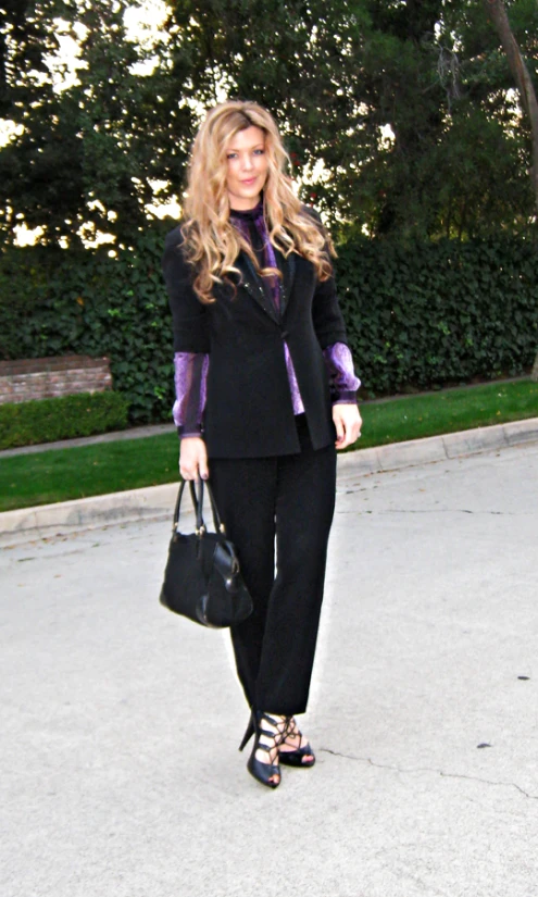 woman with shoulder bag and black pants walking down street