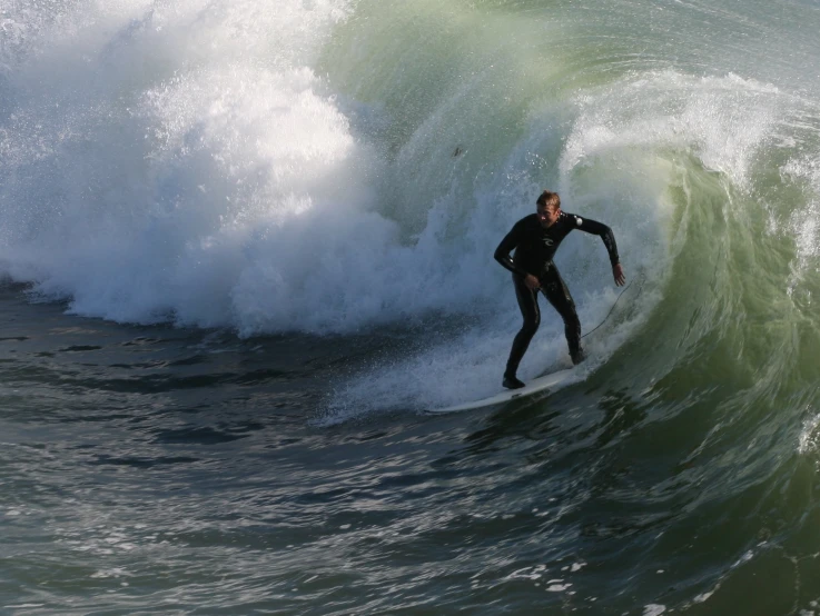 a surfer in a wet suit rides a large wave