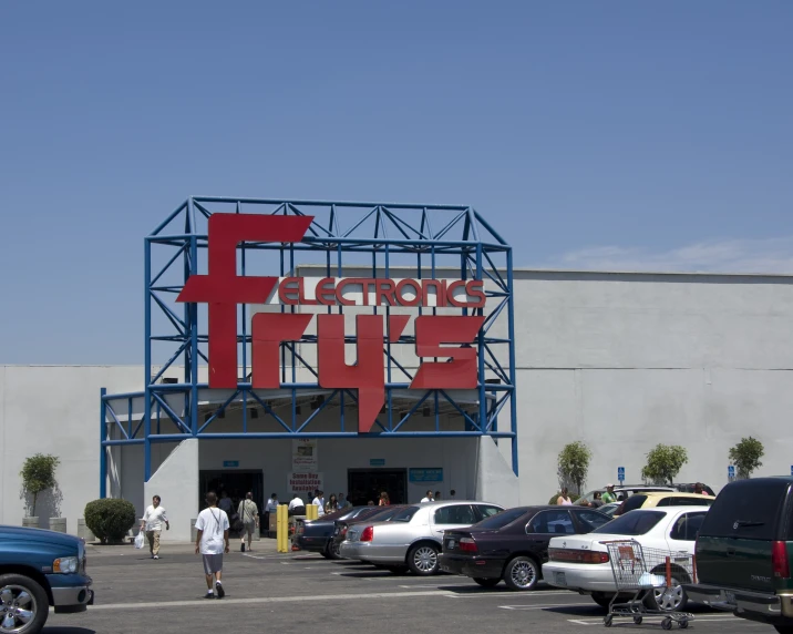 an outdoor movie theater has cars parked outside and people walk past