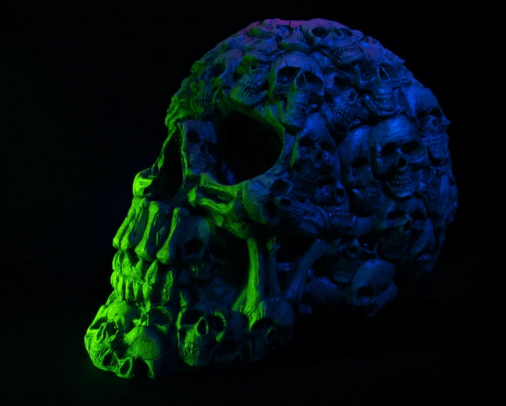 a multi colored skull in the dark with other skulls