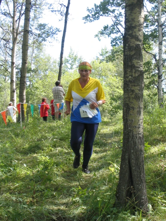 a woman standing next to a tree holding a racquet