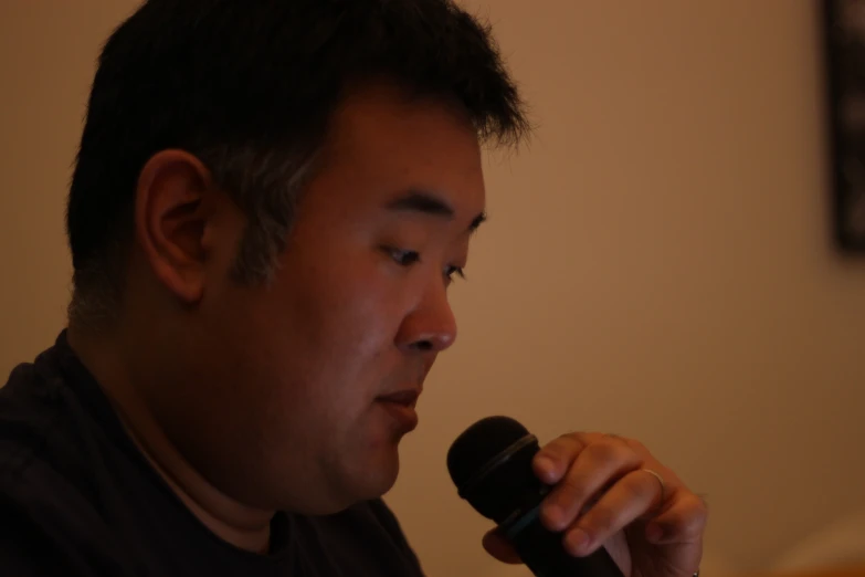 a man with black hair and beard holds a microphone up to his ear