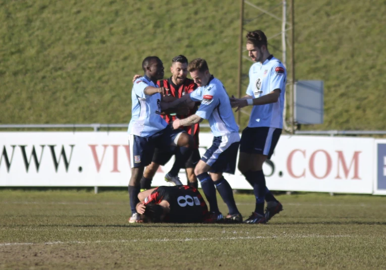 a group of people standing around each other on a soccer field