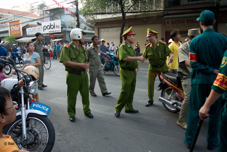 two men in uniforms standing at attention with people on motorcycles