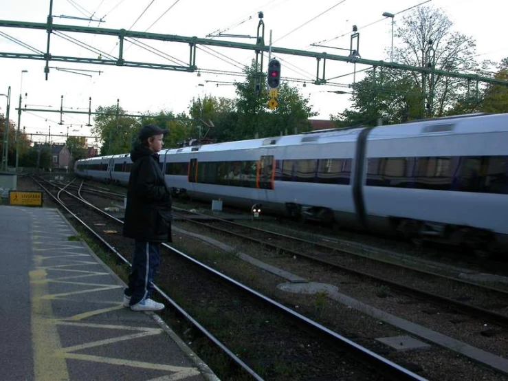 person waiting at a train station with a long train on it