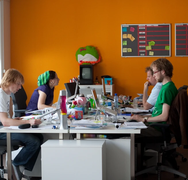 four people sitting around a table working on crafts