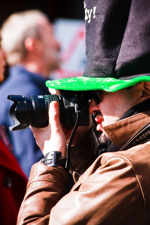 a man wearing a hat and holding a camera in front of him