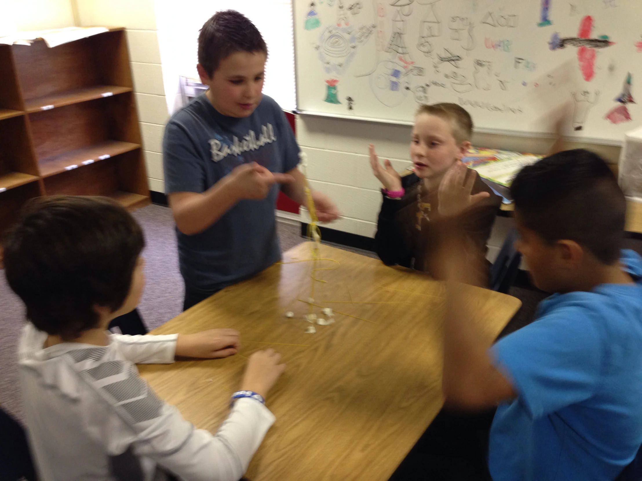 four boys stand around a desk while one holds a glass