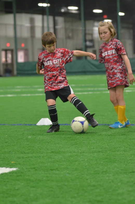 two children in uniforms playing soccer on the field