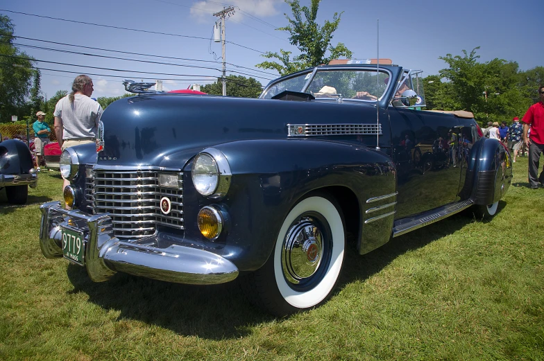 a classic blue car sitting on top of a lush green field