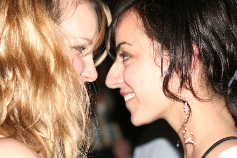 two women smile at each other as they stand next to each other