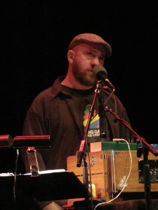 a bearded man at the microphone, listening to soing