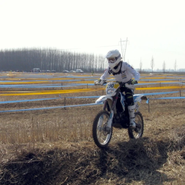 a motorcyclist dressed in white riding a dirt bike
