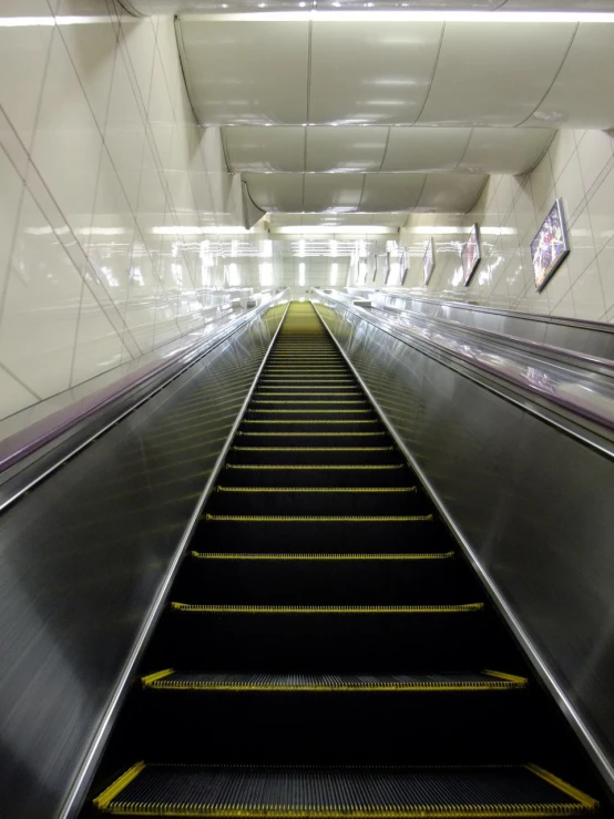 the escalator has yellow rails going through the tunnel