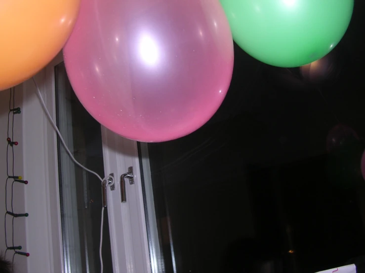 colorful balloons line a house's window at night