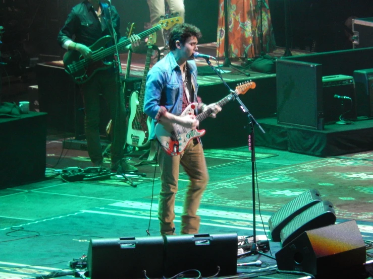 man with an electric guitar and three microphones on stage