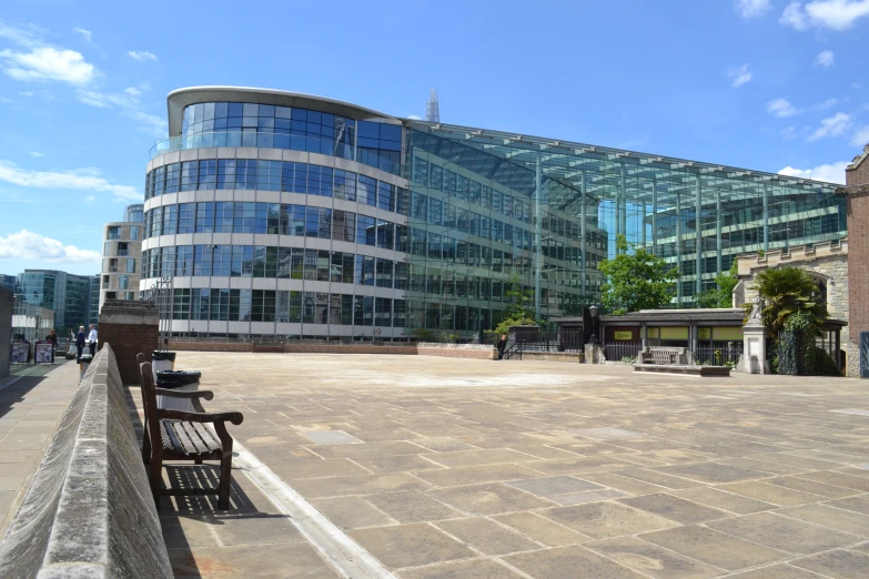 several wooden benches on a brick walkway outside a large glass building