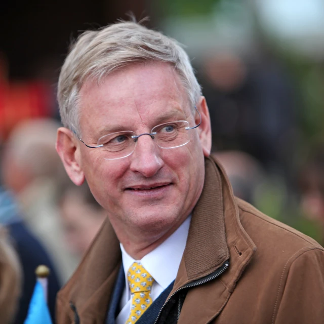 a man with glasses wearing a brown jacket