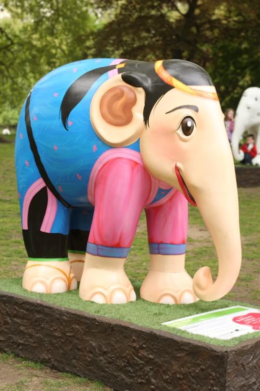 an elephant statue is in the grass near people