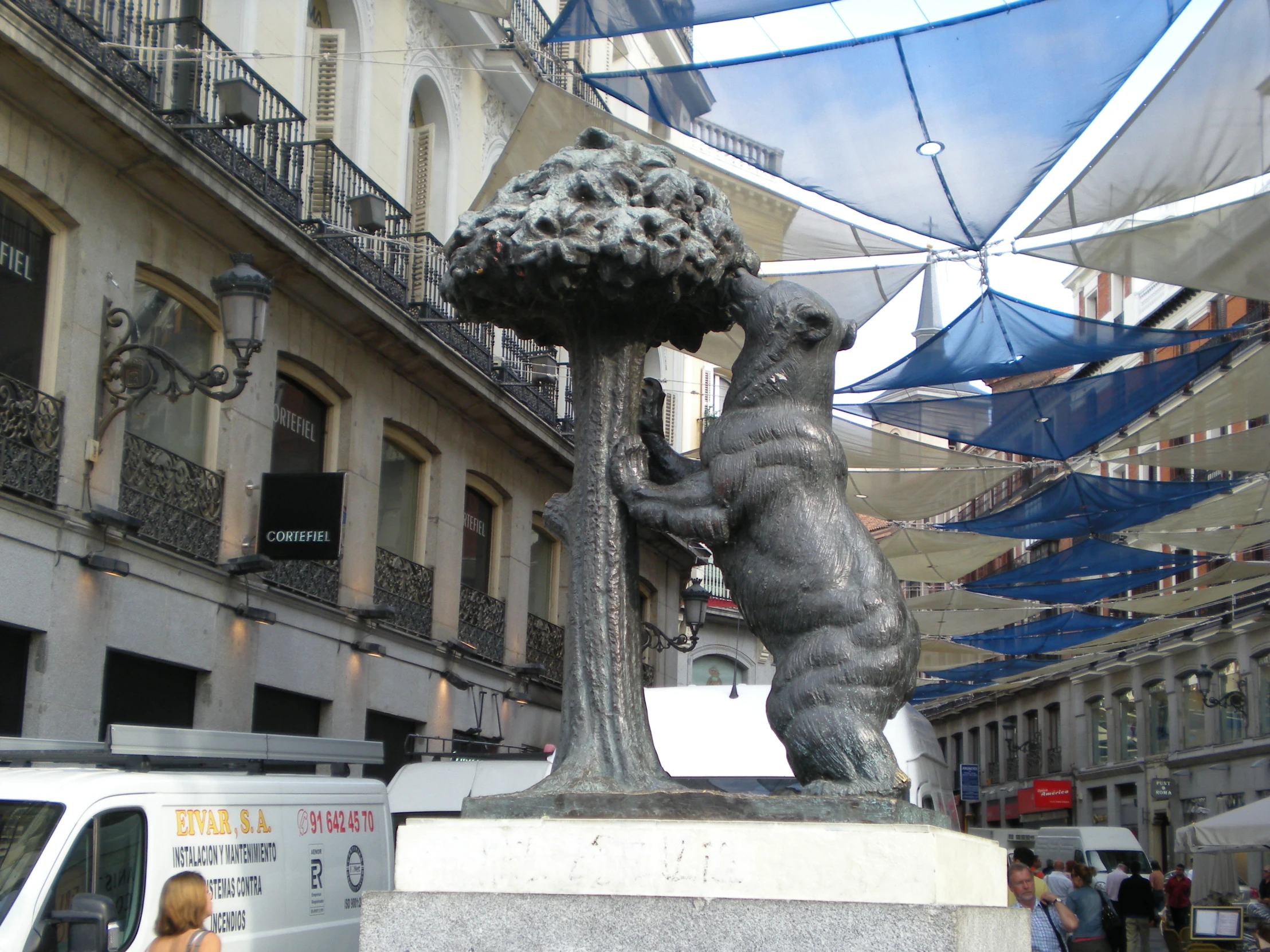 a couple of statues with umbrellas on a city street