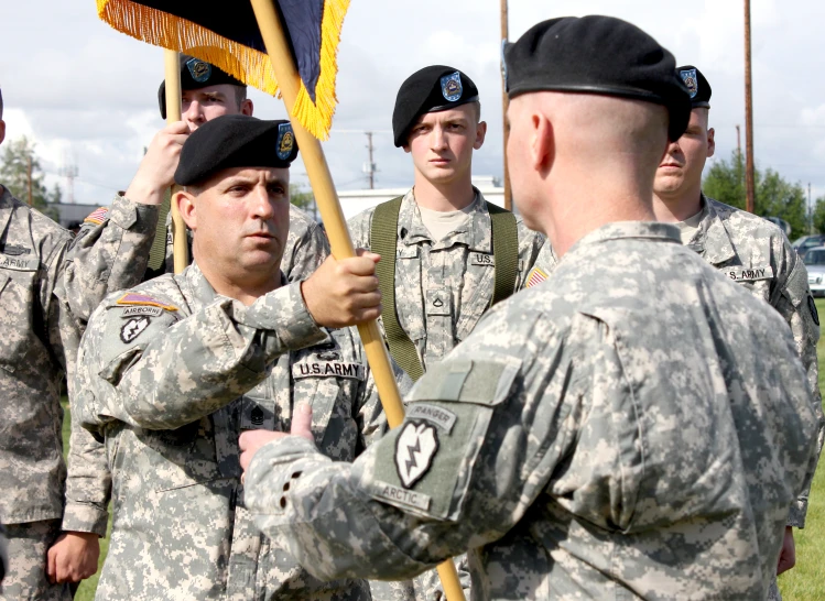 several soldiers hold up their flags in preparation to hear