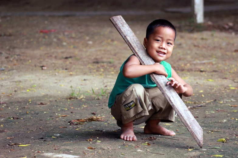 a child kneeling in the ground holding onto a cross