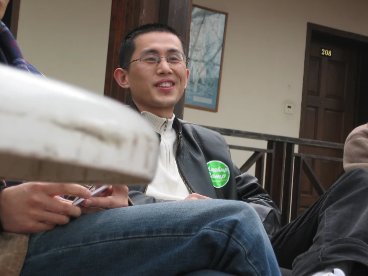 a man is holding his cell phone and showing off his green badge