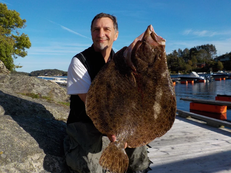 a man holds a dead fish while posing for the camera