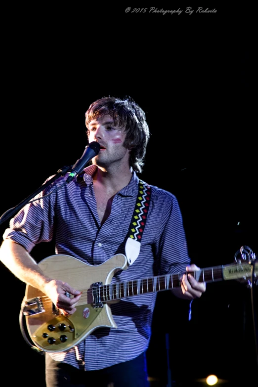 a man standing on a stage while holding a guitar