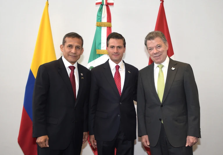 a group of men standing next to each other in front of flags