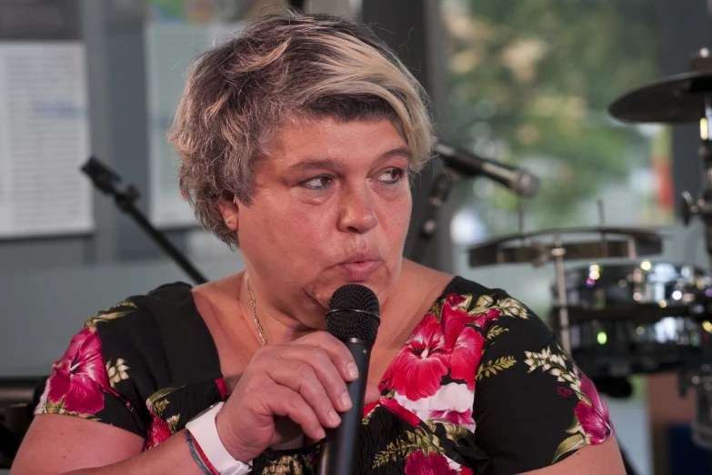 a woman in floral shirt holding a microphone