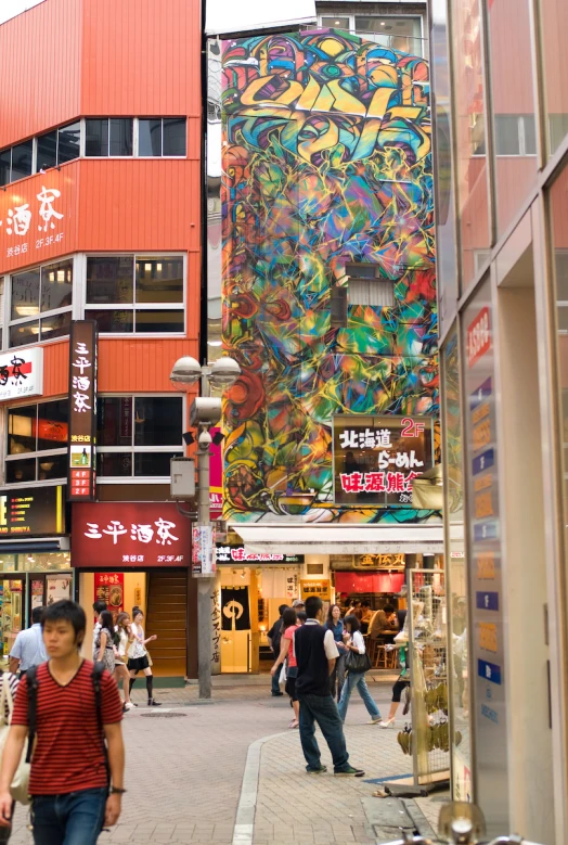 people walk on a street lined with stores