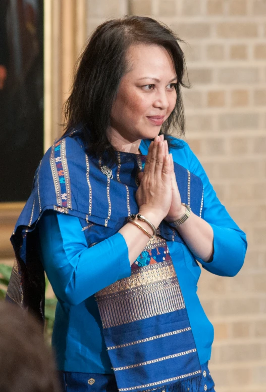 an asian woman standing and praying in front of a mirror