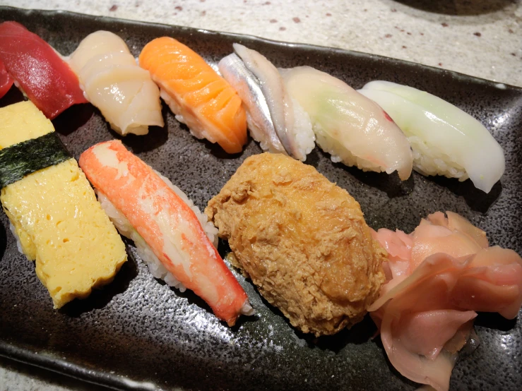 an assortment of sushi is shown on a black tray