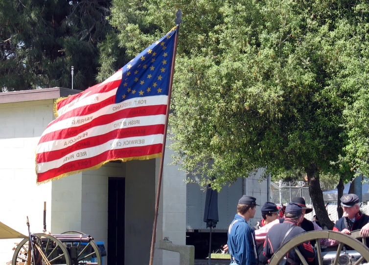 people are standing under an american flag