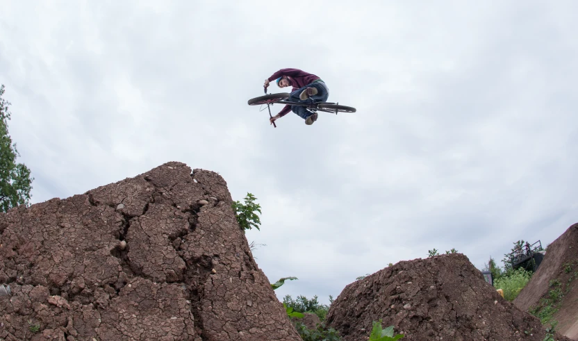 person wearing black riding equipment jumping over boulders