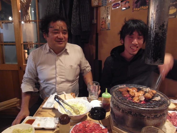 two asian men sitting down to eat at a table