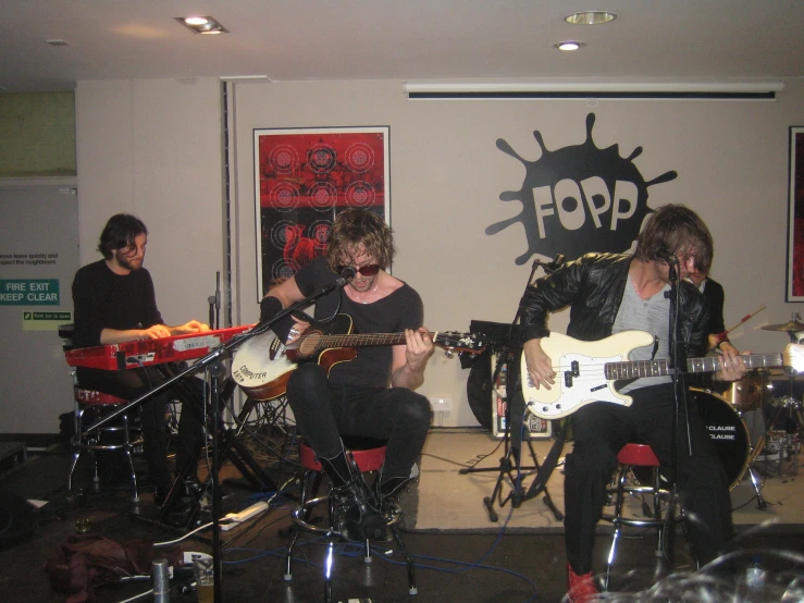 a group of people sitting around on stage playing musical instruments