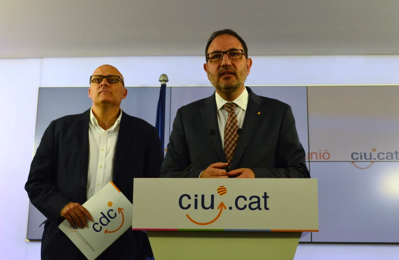 two men standing behind a podium while one is holding papers