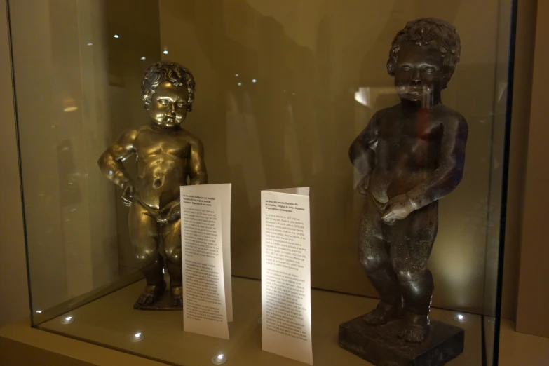 two statues and some white papers in a glass case
