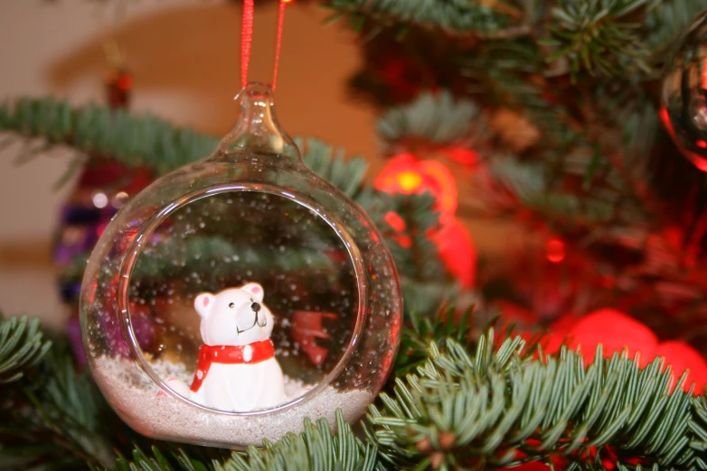 a christmas ornament has a bear in the snow inside